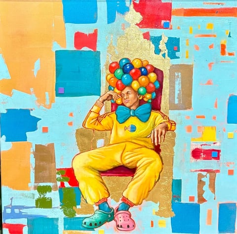 Person in bright yellow outfit and blue bow tie sitting in cardboard chair surrounded by colorful balloons and geometric background